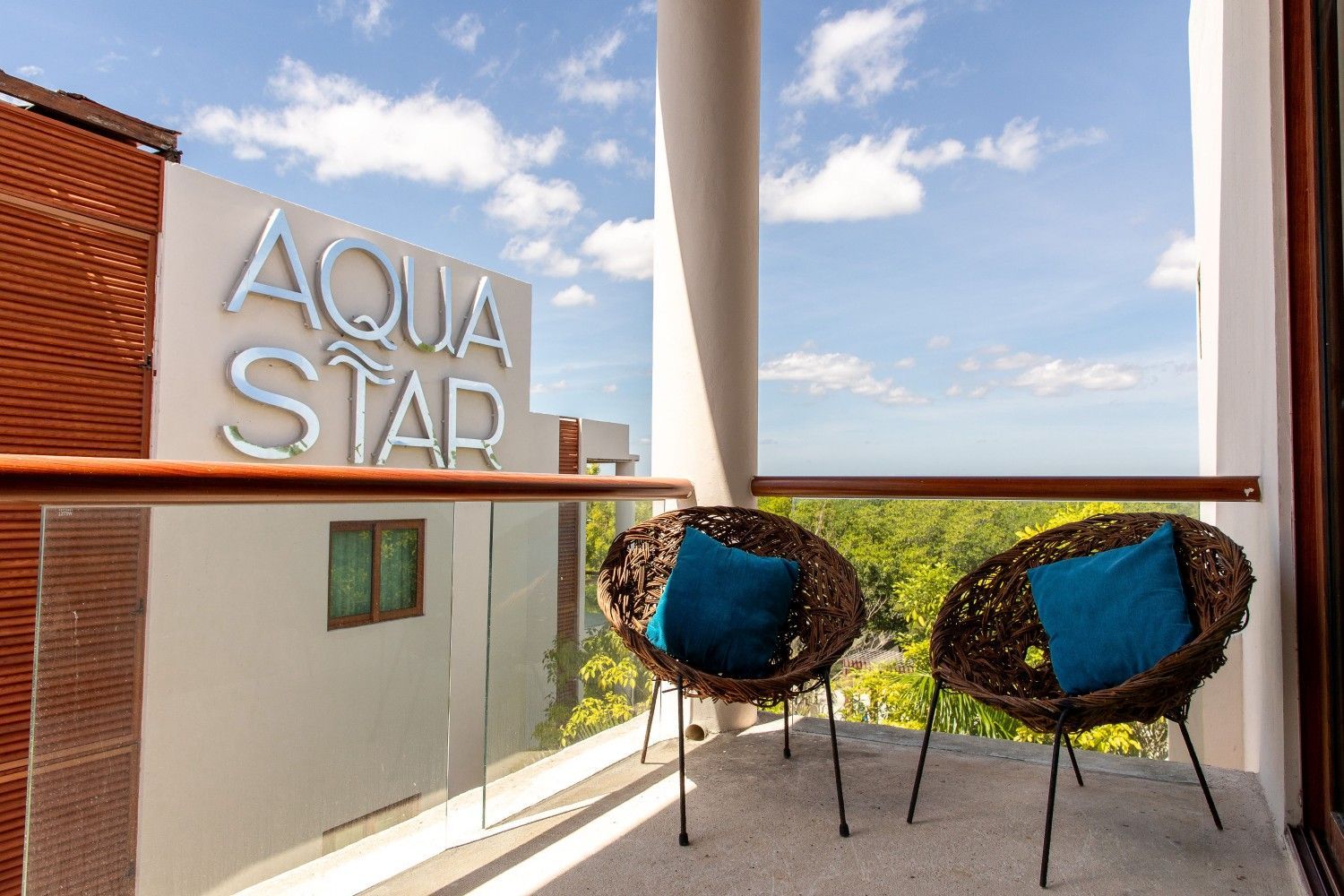 Balcón con dos sillas con cojines azules con vistas al edificio Aqua Star y al horizonte del océano.