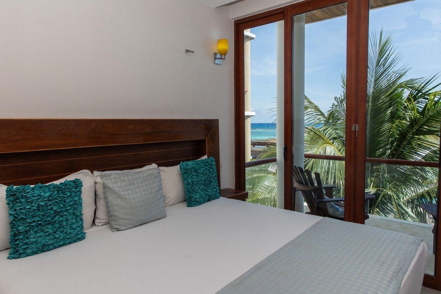 Habitación con cama king y vista al mar a través de puertas de cristal.