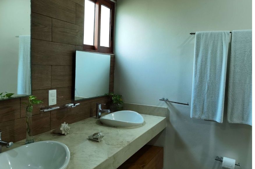 Baño con dos lavabos, un espejo grande y toallas colgadas en la pared.