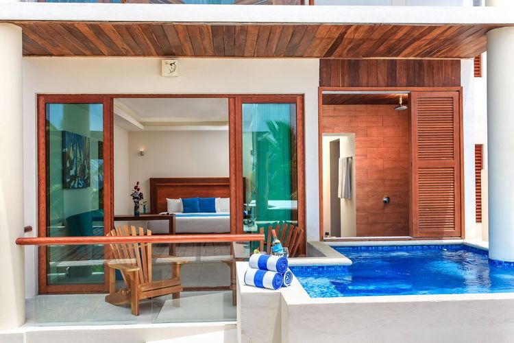 Patio de lujo en la villa con puertas corredizas de vidrio, sillas de madera y una pequeña piscina con azulejos azules.