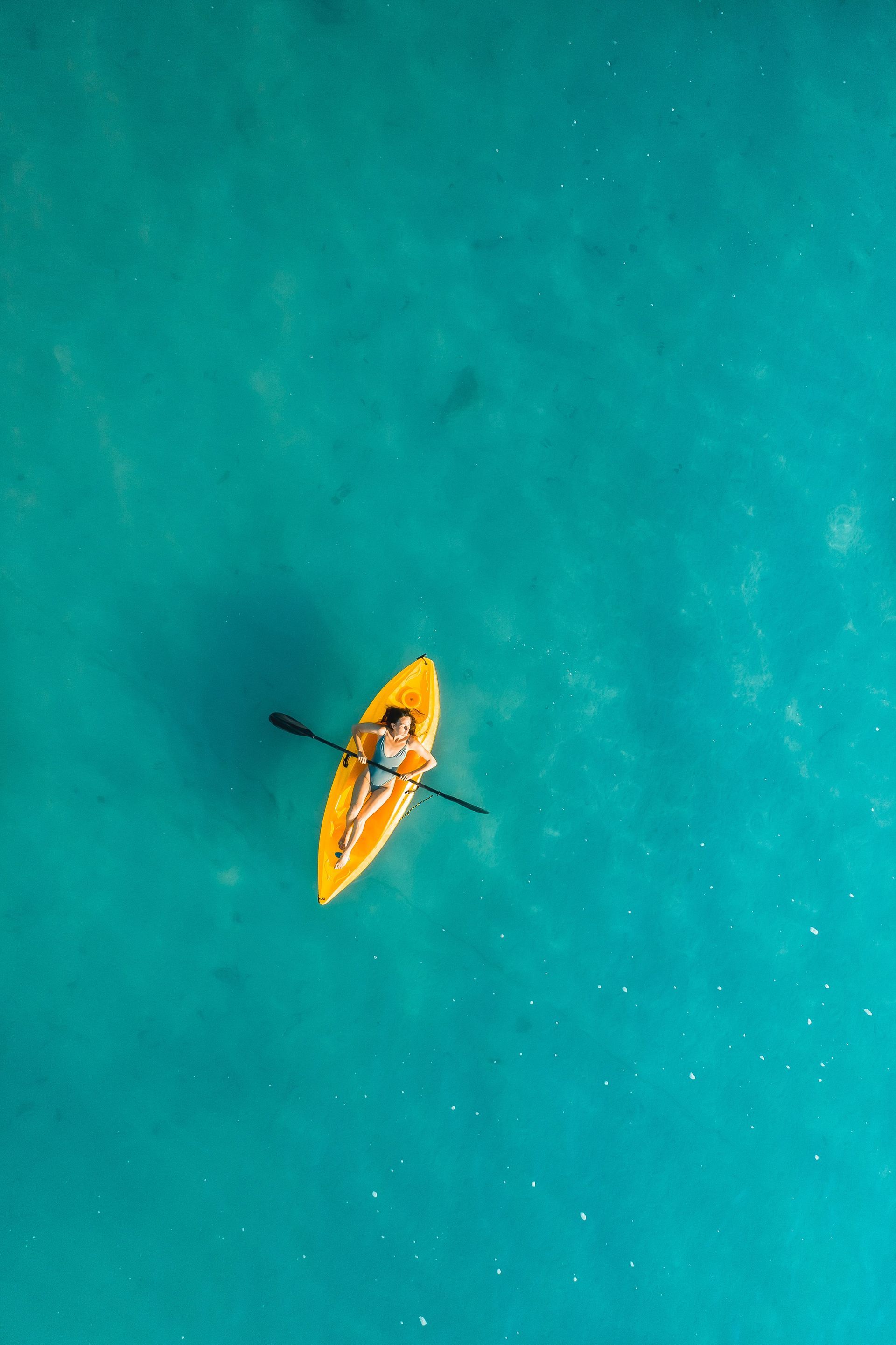 Un kayak amarillo solitario sobre aguas turquesas, visto desde arriba.
