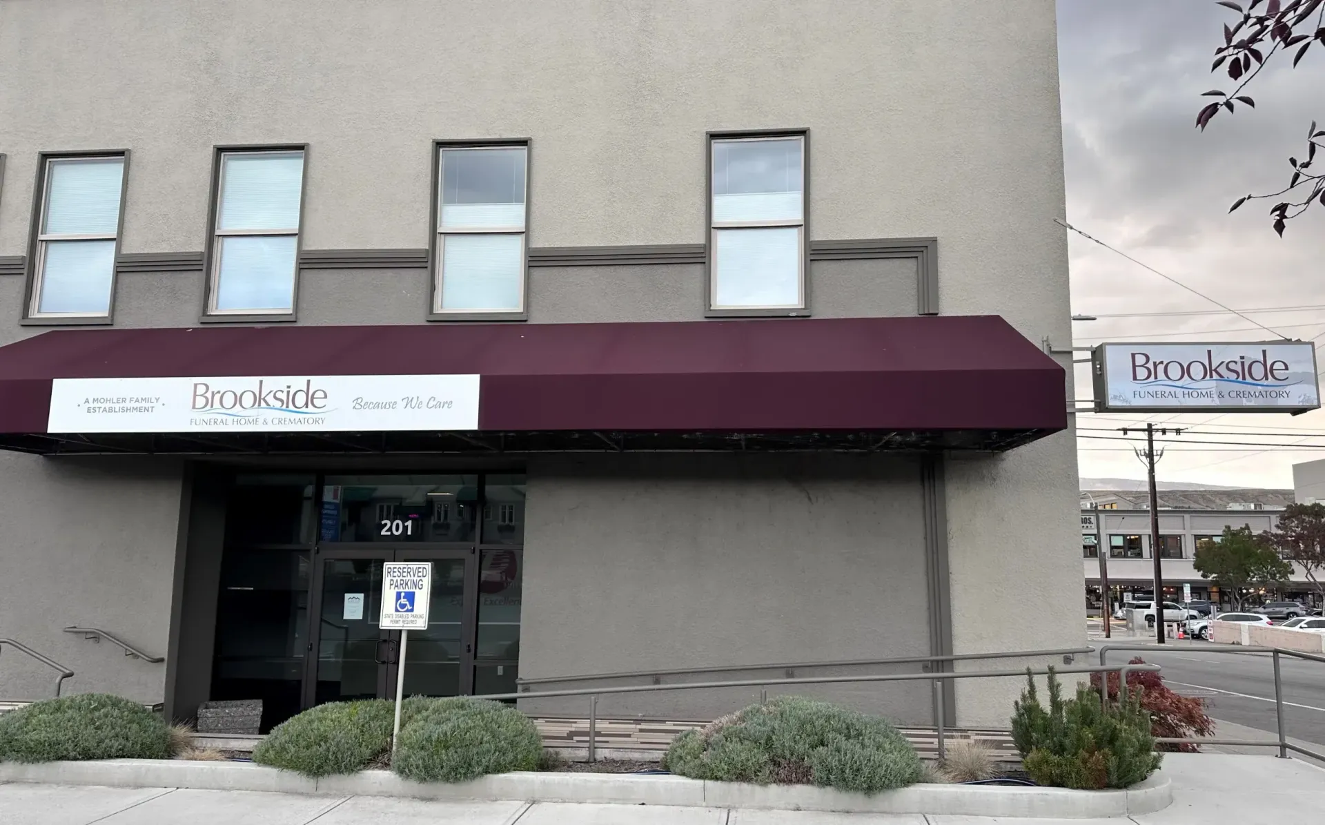 Building exterior with burgundy awning, windows, and sign that says 