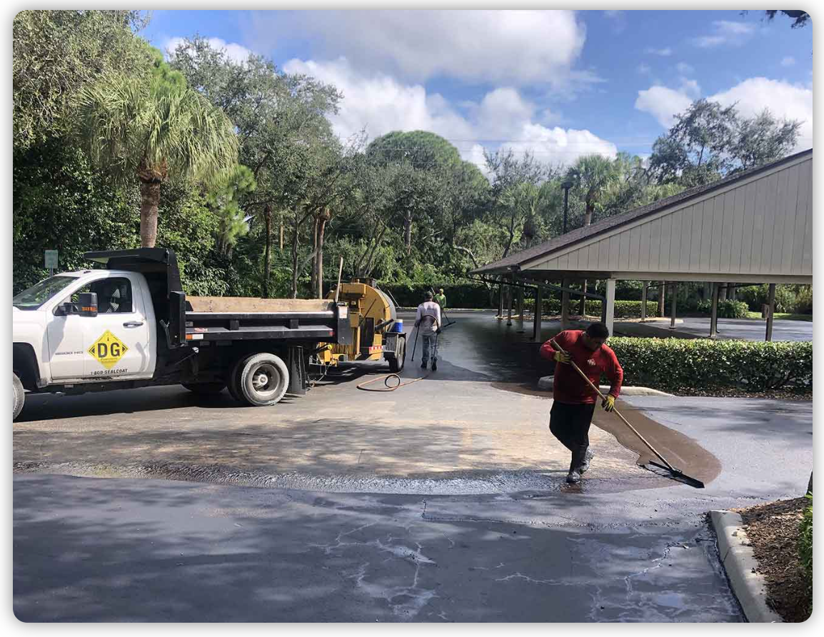 A man is cleaning a driveway next to a truck.