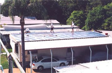 Two men are working on the roof of a mobile home