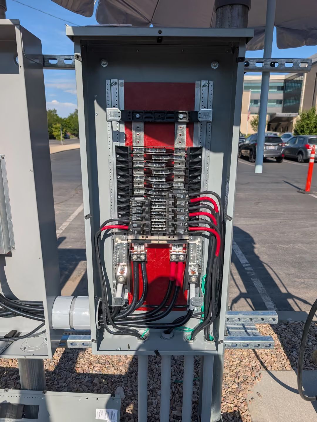 Open electrical breaker panel with wiring and red cables in an outdoor utility area