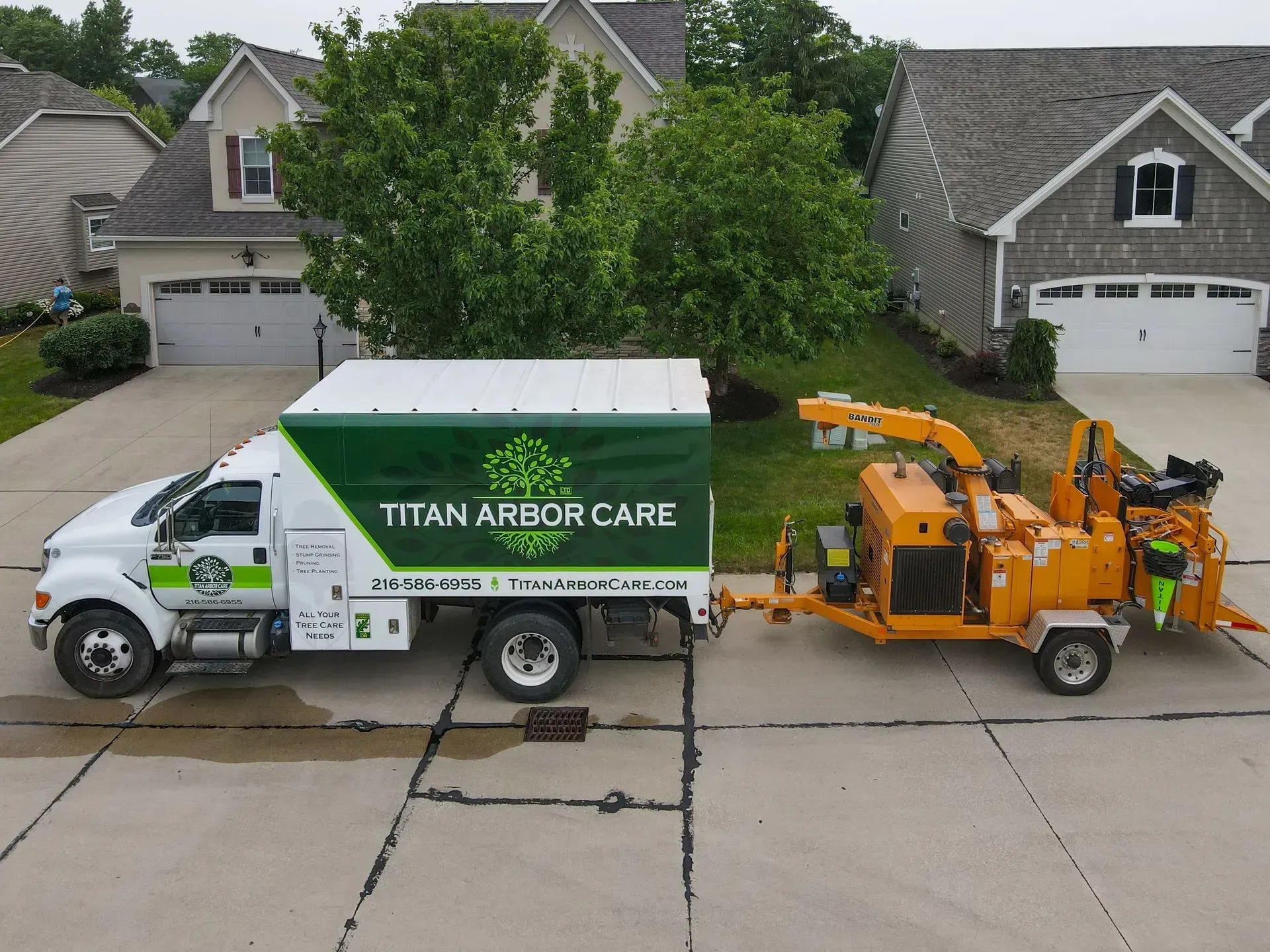 Titan Arbor Care truck with wood chipper trailer parked in a residential driveway.