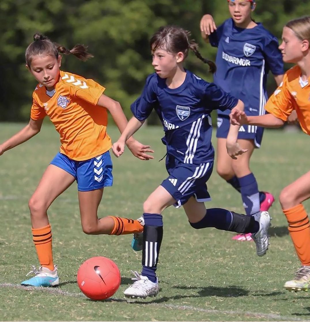 Sporting Arkansas Academy player during game against team in orange.