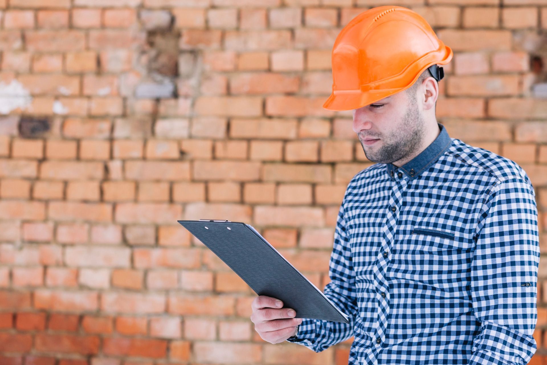 Home inspector checking cracks, mortar joints, moisture, and movement along a brick foundation wall.