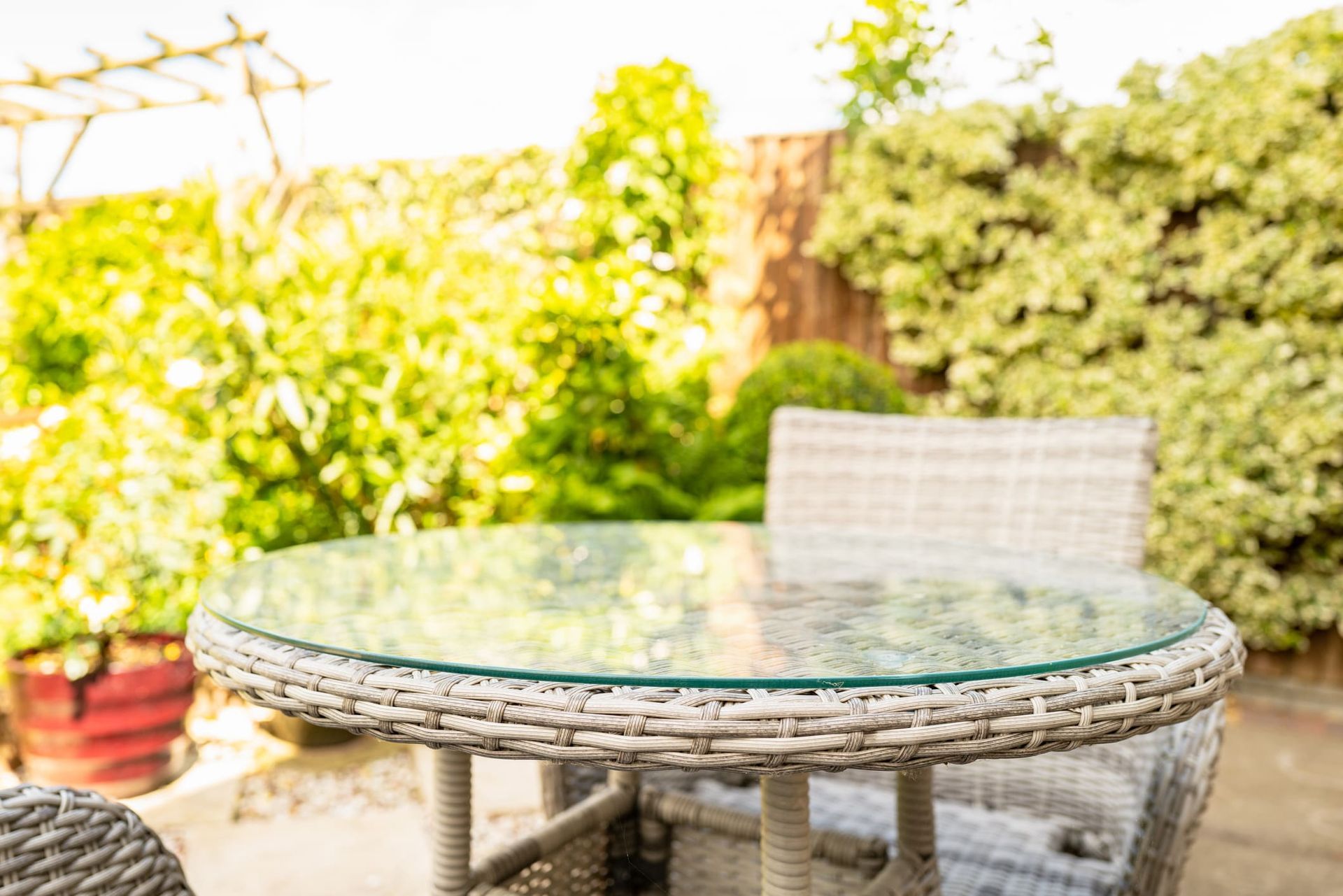 A wicker table and chairs on a patio with a glass top.