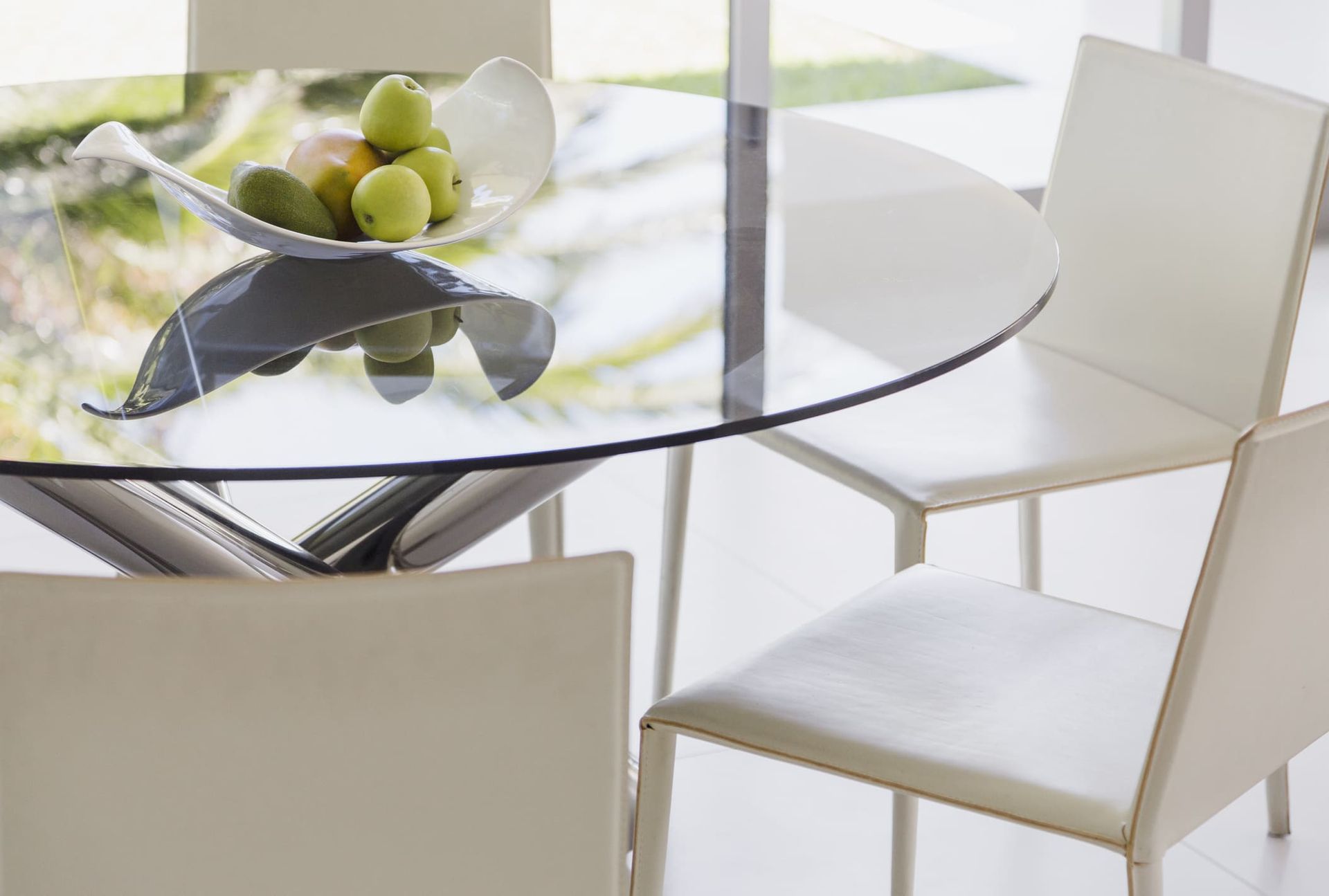 A glass table with a bowl of fruit on it.