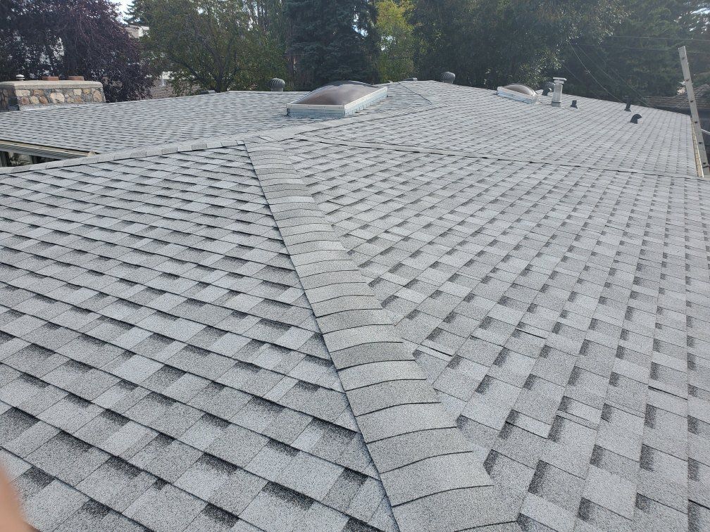 A roof with a lot of shingles and a skylight on it.