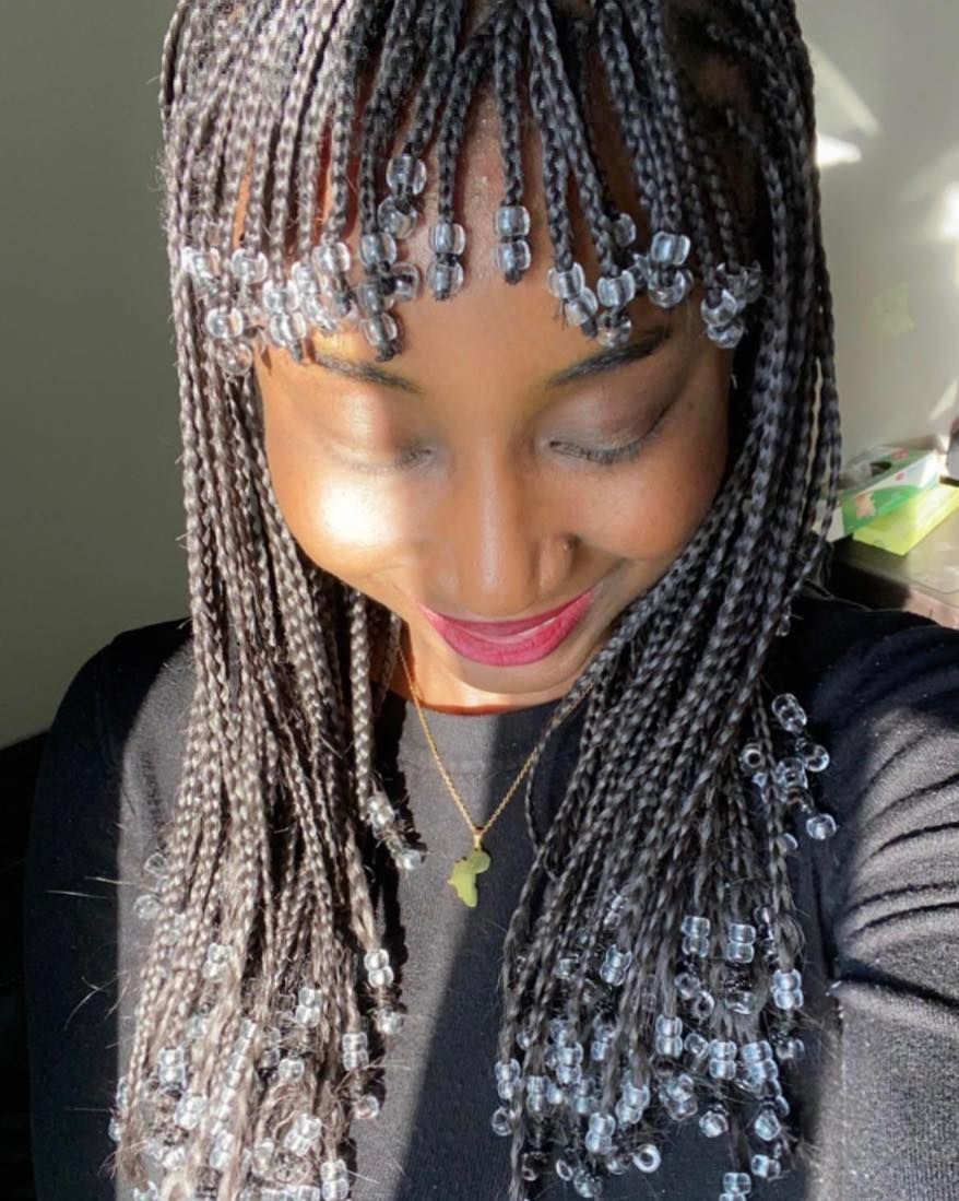 A man with braids in his hair is sitting in a chair.