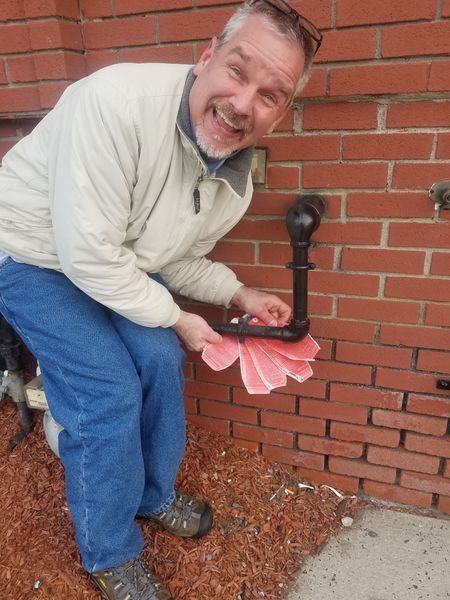 A man is kneeling down in front of a brick wall holding a flower