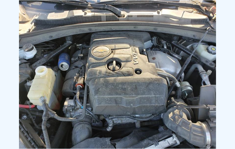Dirty car engine bay with plastic covers, coolant tank, and air intake hoses.