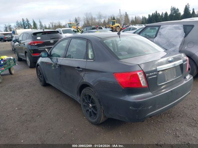 Dark gray Subaru sedan in a junkyard, rear view.