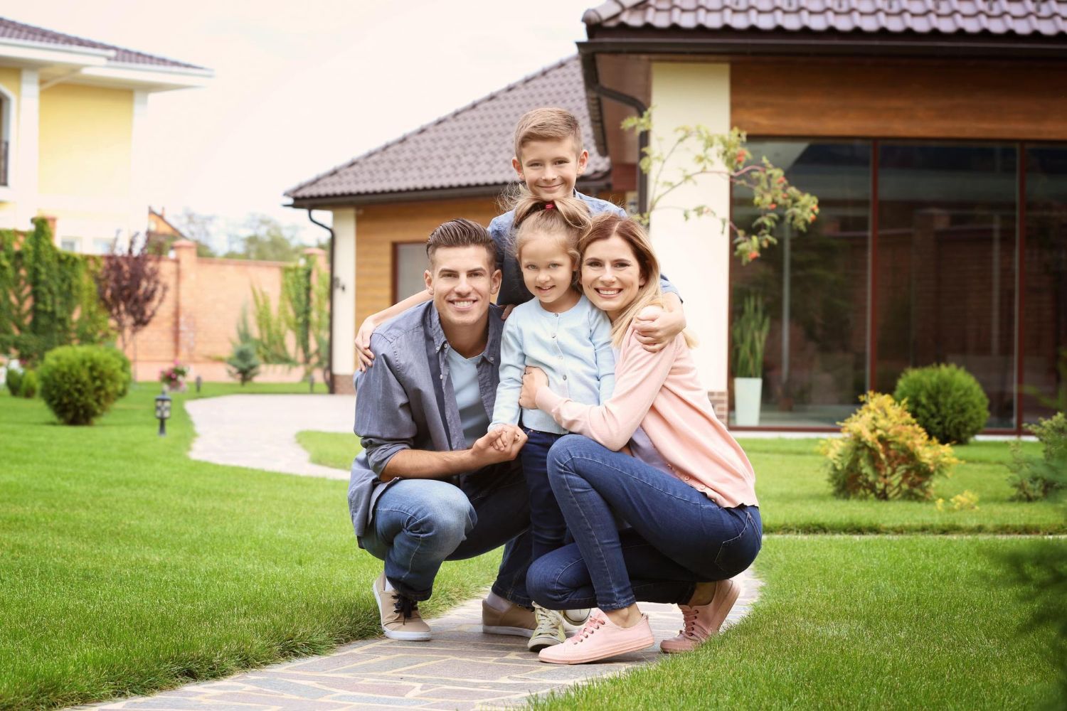 A family is posing for a picture in front of their new home.