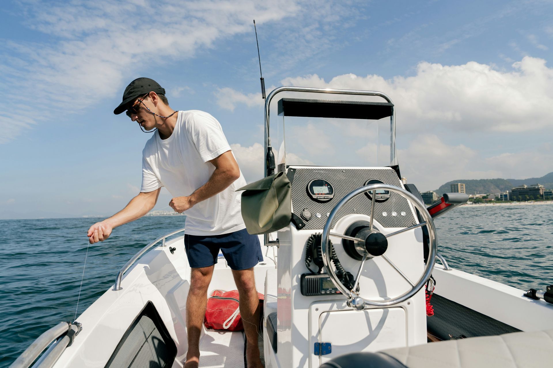 A man is sitting at the steering wheel of a boat.