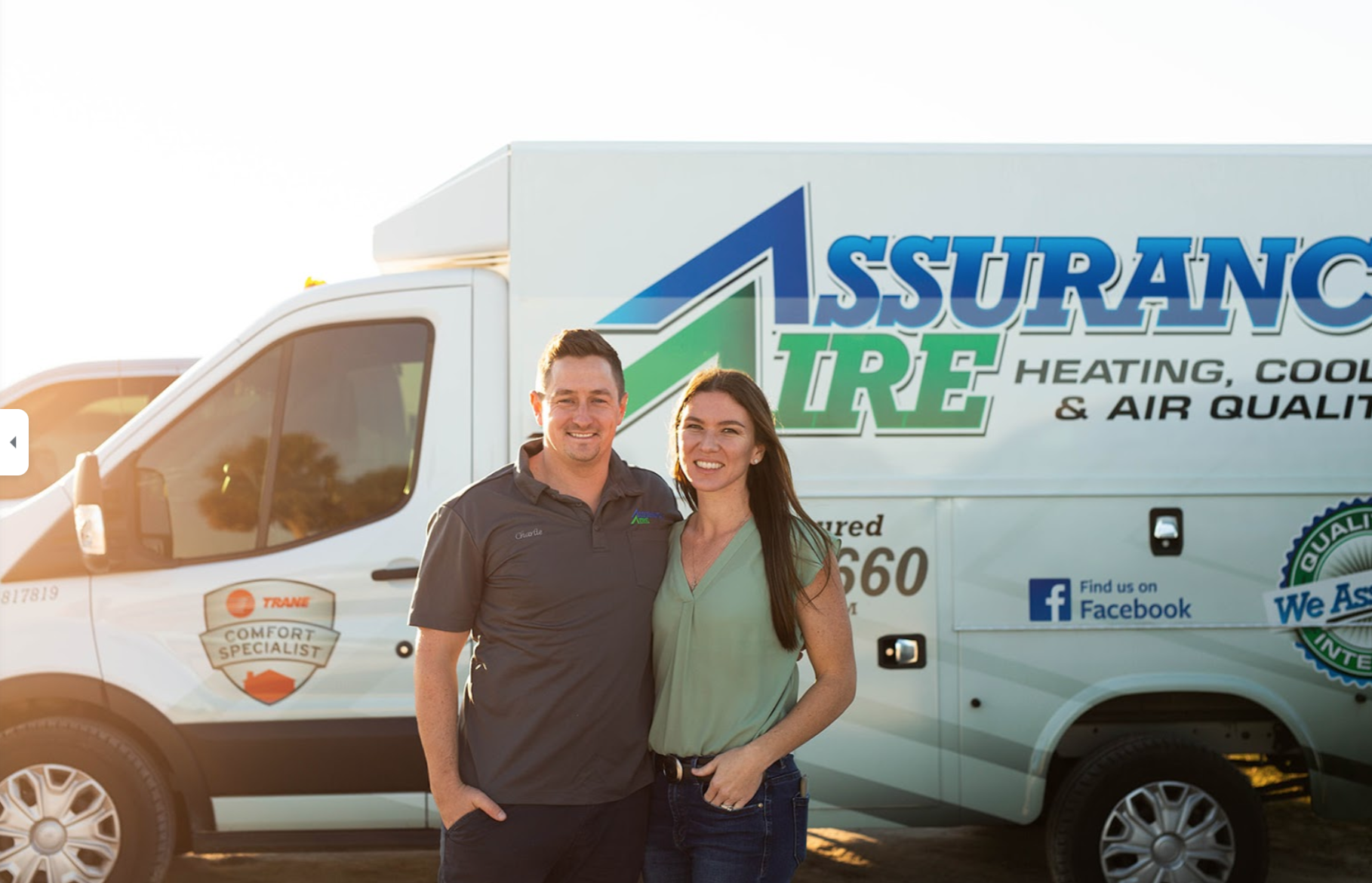 A smiling duo stands in front of a white service van for Assurance Aire Heating, Cooling, and Air Quality.