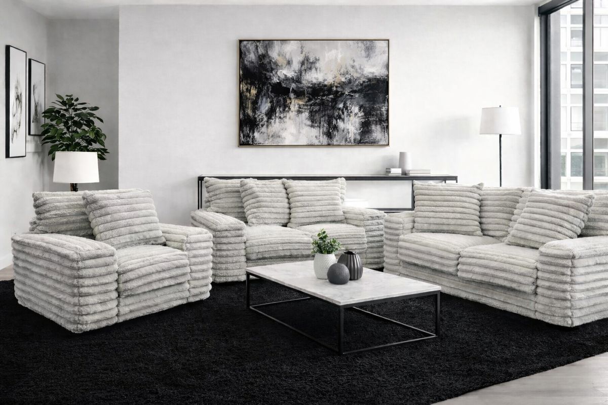 Living room with white and gray textured furniture, black rug, and abstract art.