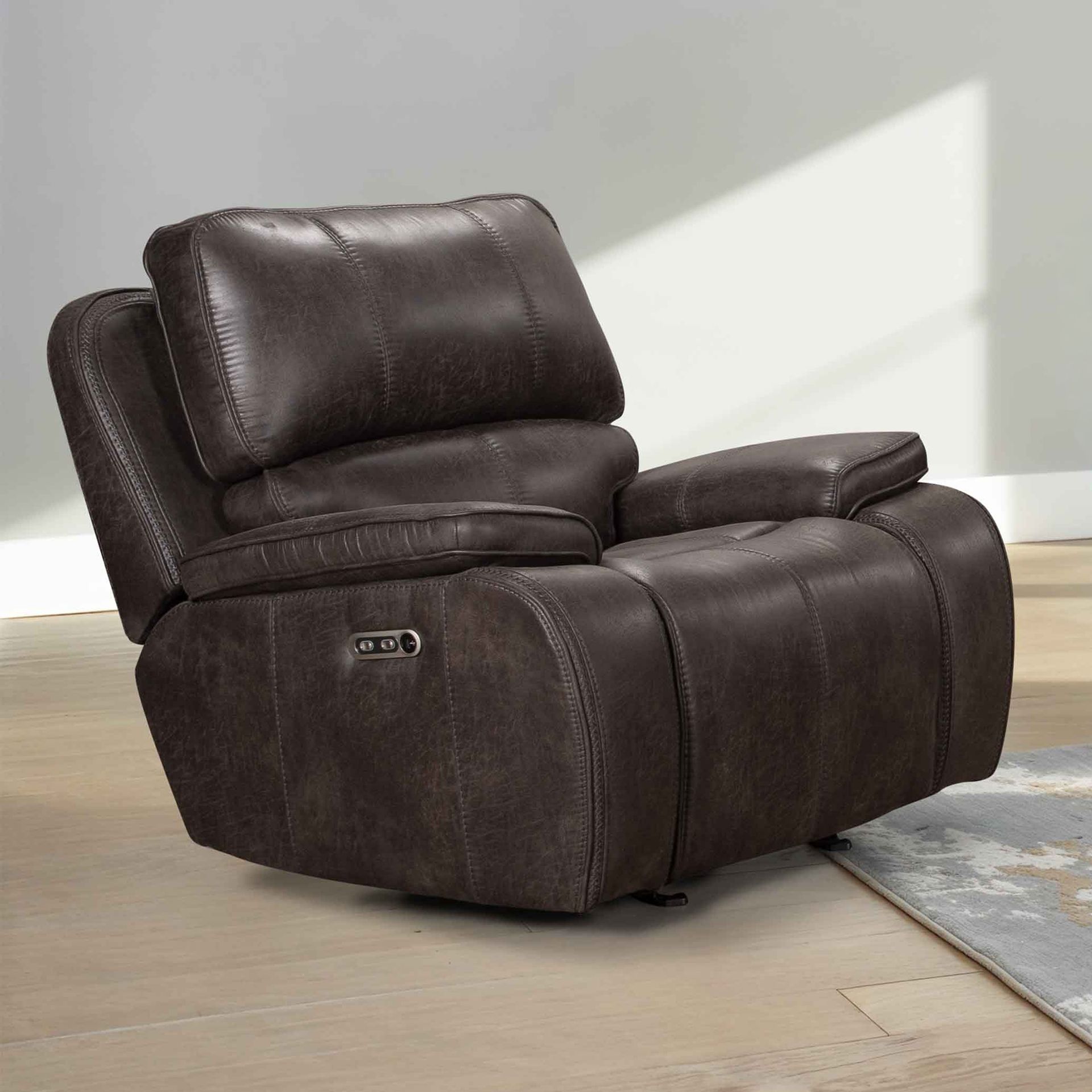 A dark brown leather power recliner armchair with a padded headrest and armrests, set in a neutral indoor room.