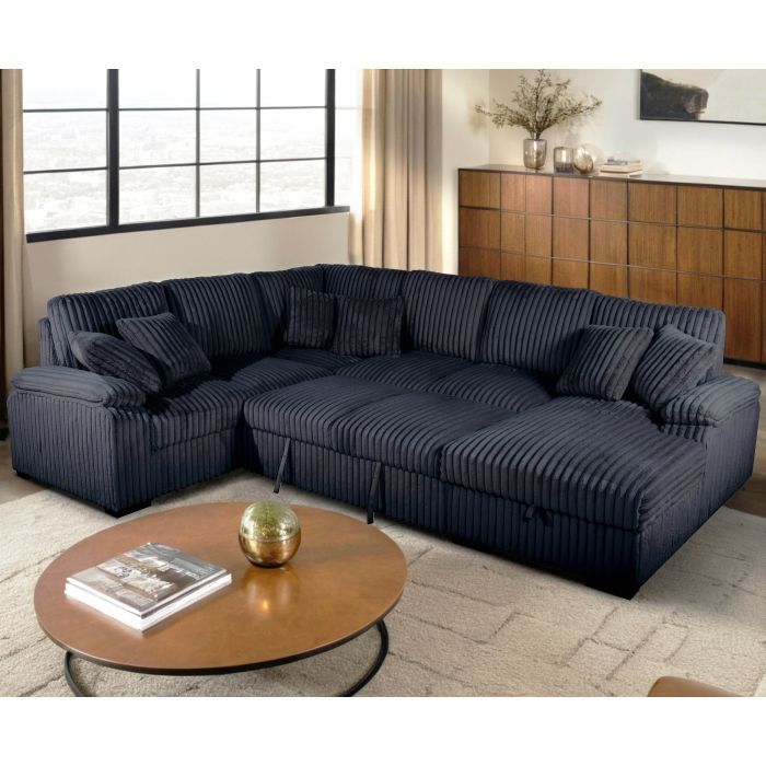 Navy corduroy sectional sofa in a living room, with pillows, a coffee table, and a cabinet.