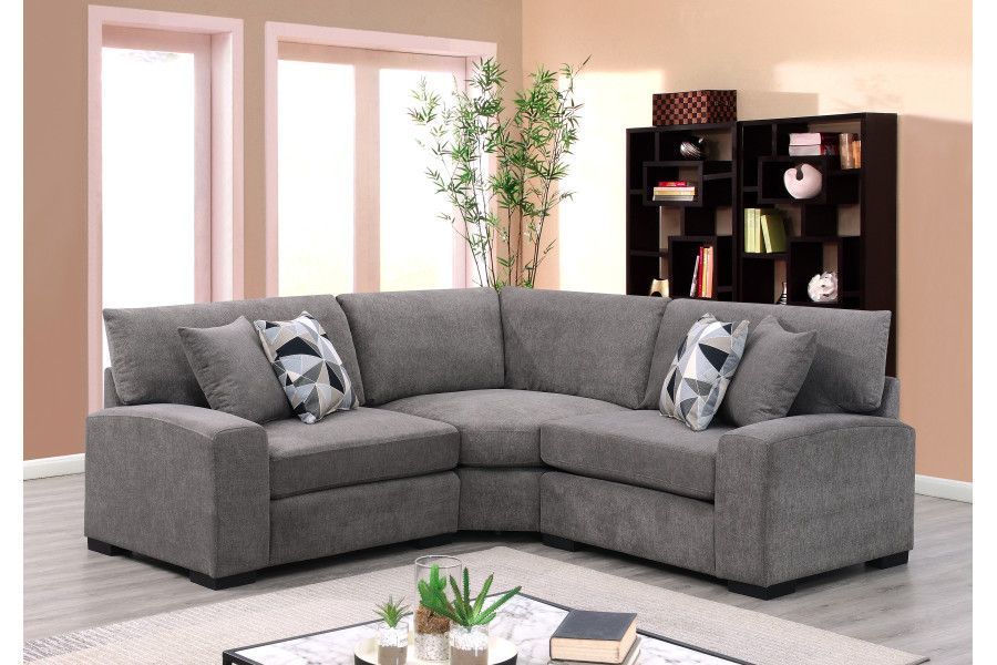 Gray sectional sofa in a living room, with accent pillows and a bookcase.