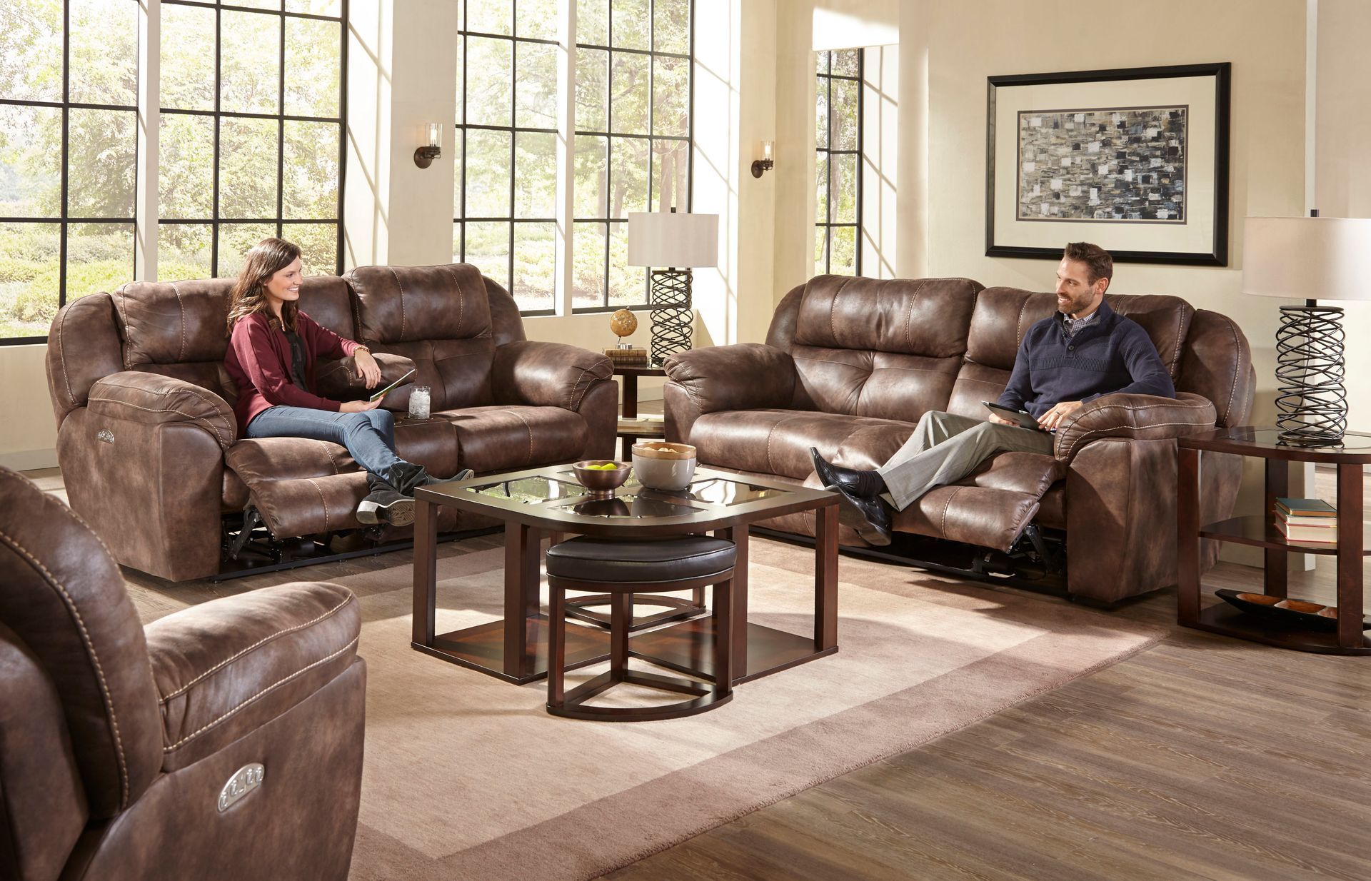 Living room with brown reclining sofas, coffee table, two people seated.