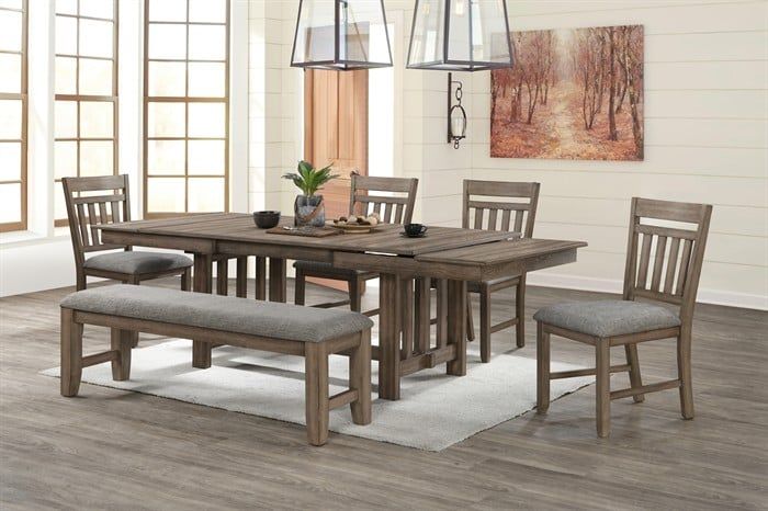 A rustic dining set with a wooden table, two chairs, and a long bench with gray upholstered seats on a light rug.