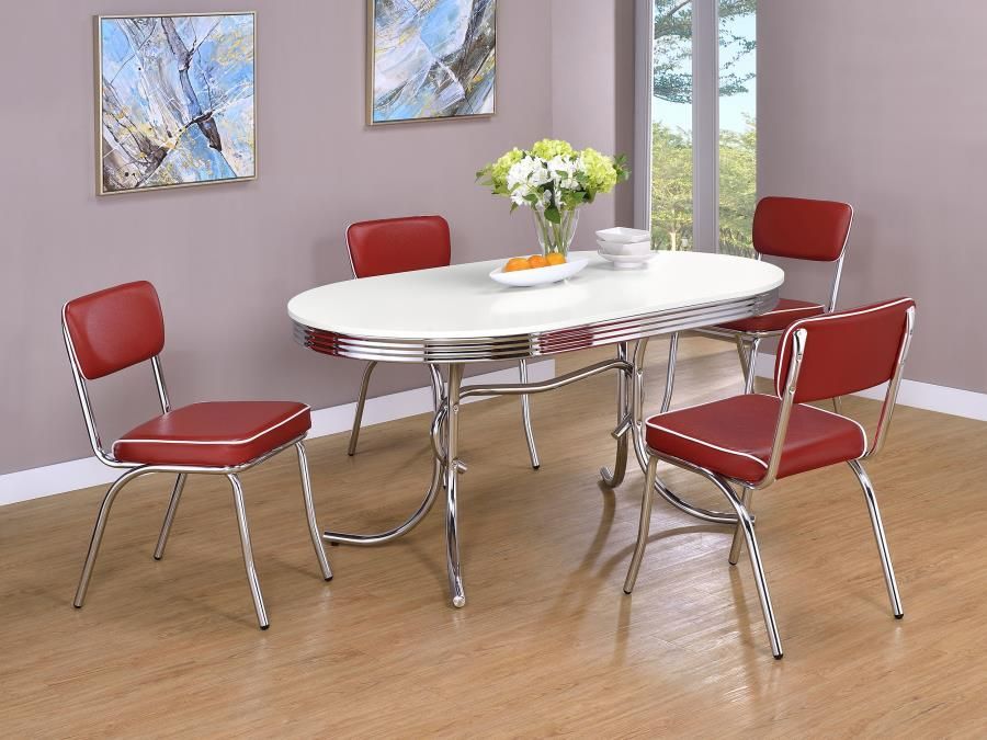 Red chairs surround a white and chrome retro dining table in a bright room.