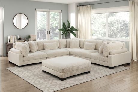 Living room with a large cream sectional sofa, matching ottoman, and rug.