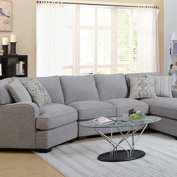 Gray sectional sofa in a living room with a glass coffee table and window.
