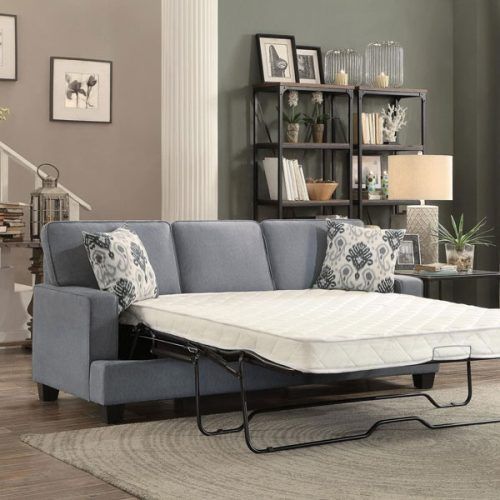 Blue pull-out sofa with mattress extended. Living room with shelving, artwork, and lamp.