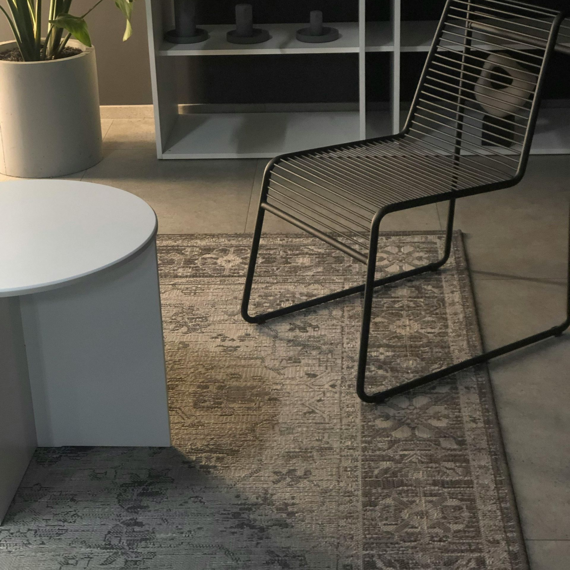 A modern interior with a rug, chair, and side table. Grey and white tones.