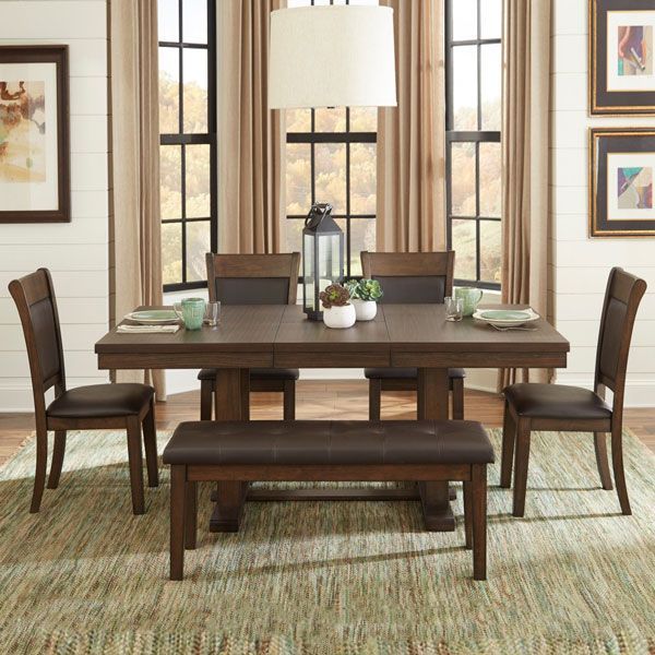 Dining room set: wooden table, chairs, bench, rug, windows with drapes, artwork, and a hanging light.
