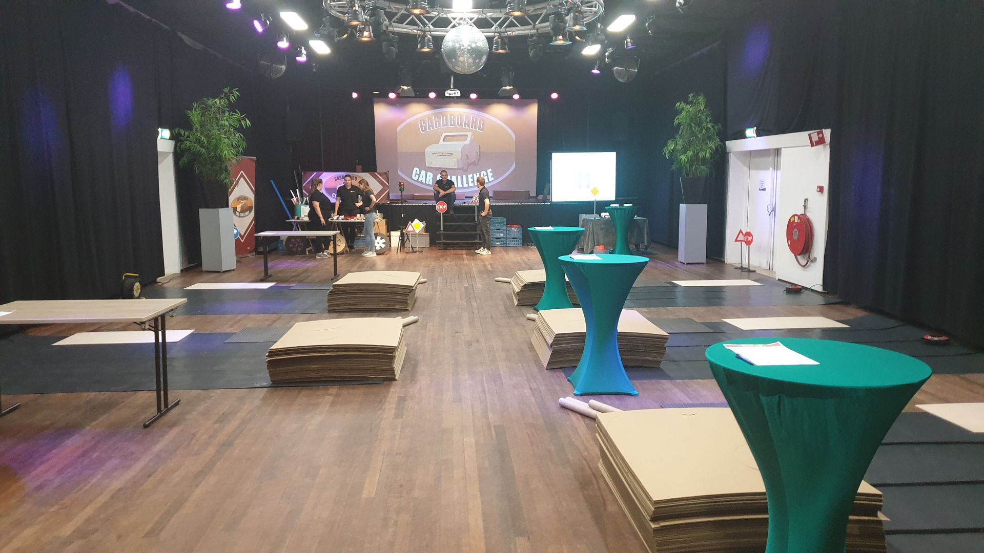 Een grote kamer met tafels en dozen op de vloer.