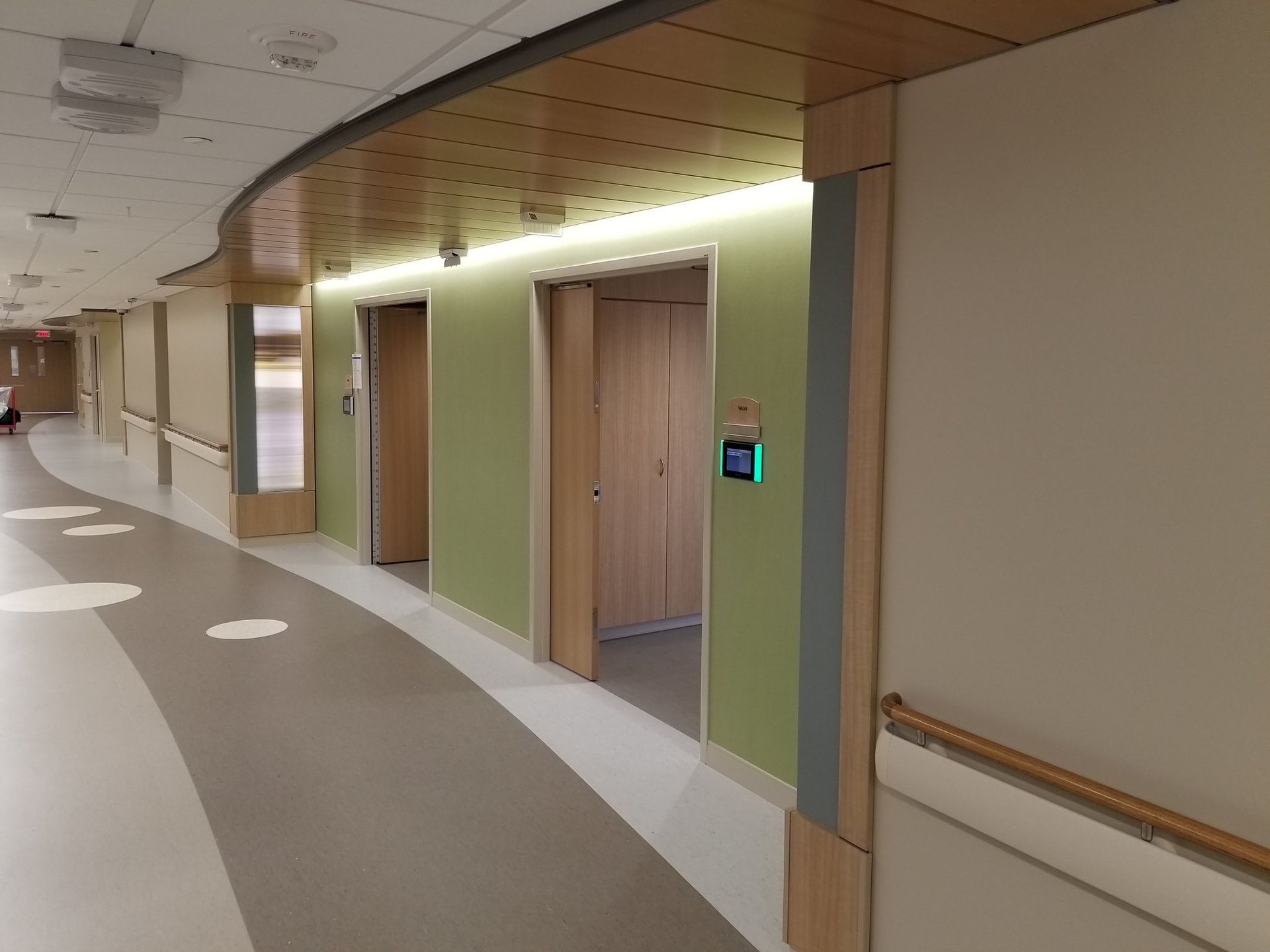 A long hallway in a hospital with a green light on the wall.