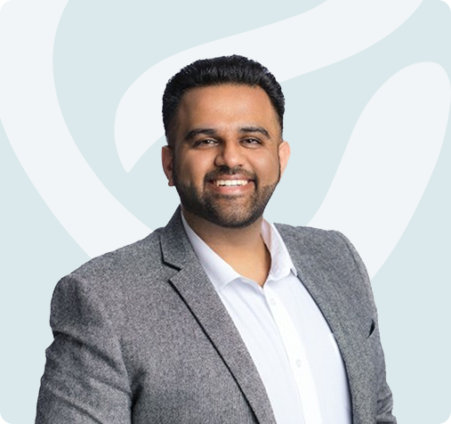 Smiling man in a gray blazer and white shirt against a light abstract background