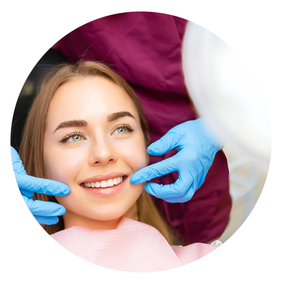 Dentist examining a smiling patient’s teeth with blue-gloved hands