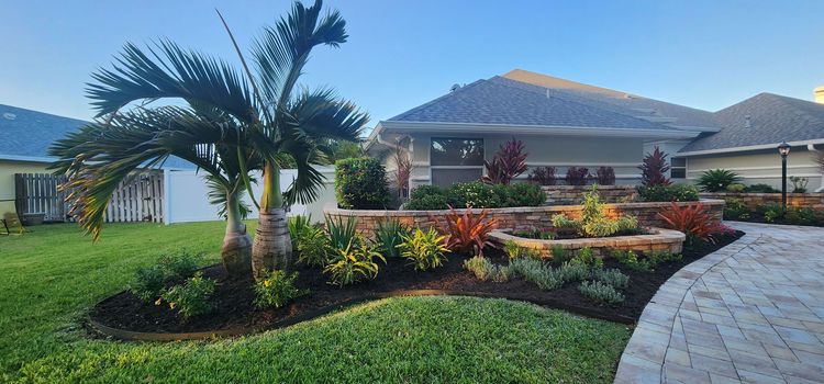 Landscape lighting in a rock garden with palm plants and a glowing decorative stone at dusk