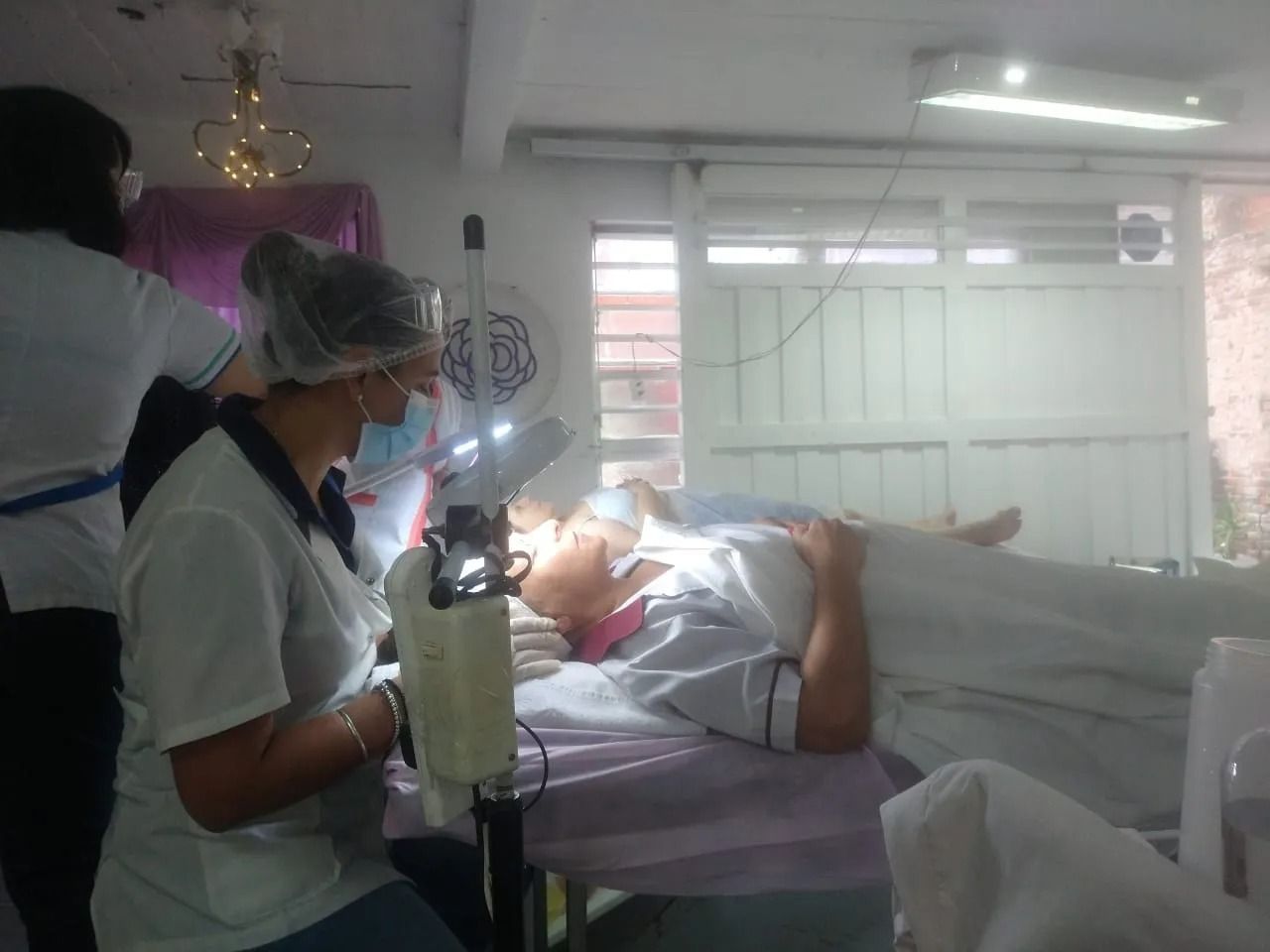 Un dentista examina a un paciente en una clínica luminosa, con una lámpara dental y el equipo a su alrededor.