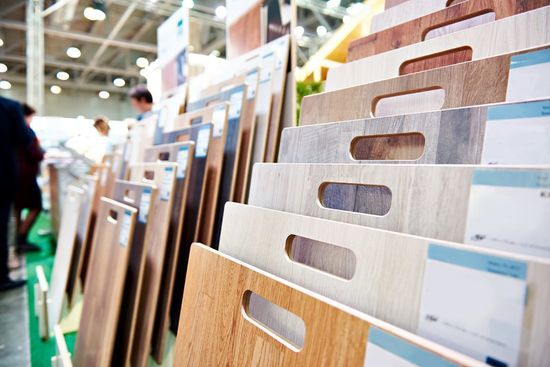 File di pannelli campione di legno in uno showroom, con una persona che li osserva sullo sfondo.