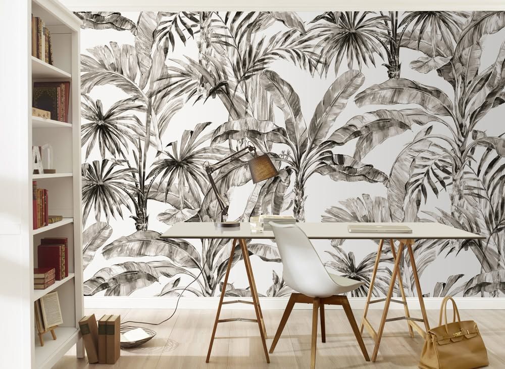 Moderno ufficio domestico con carta da parati tropicale, scrivania e sedia bianche.