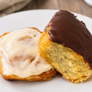 Two glazed donuts, one vanilla and one chocolate, on a white plate