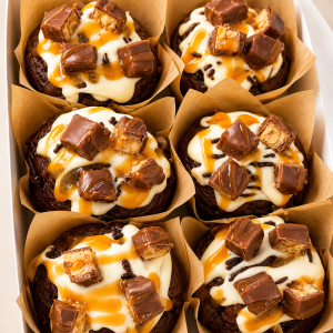 Six caramel-drizzled cupcakes topped with chocolate chunks in brown paper liners