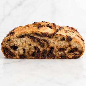 Loaf of chocolate chip bread with a golden crust on a white background