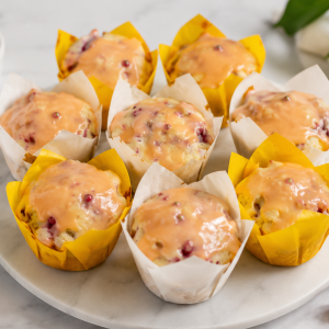 Plate of glazed muffins in white and yellow paper liners