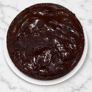 A bowl of glossy dark chocolate batter on a white marble surface