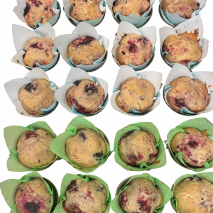 Assorted blueberry muffins in white and green paper liners, arranged in a grid on a light background