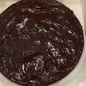 A bowl of glossy dark chocolate batter or frosting with a swirled surface