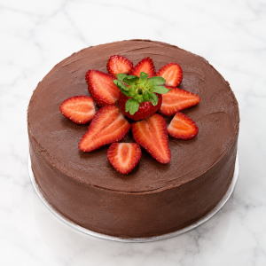Chocolate cake topped with sliced strawberries on a white plate